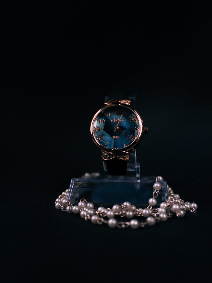 Elegant wristwatch with pearls on dark background, showcasing luxury fashion.