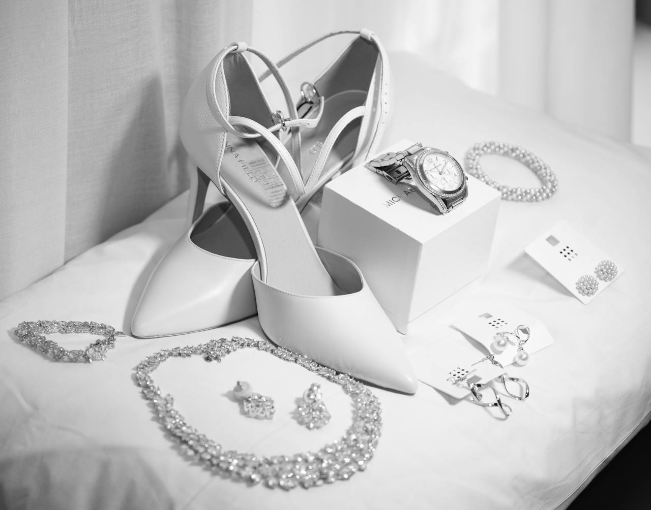 A collection of elegant bridal accessories including shoes and jewelry in a monochrome setting.